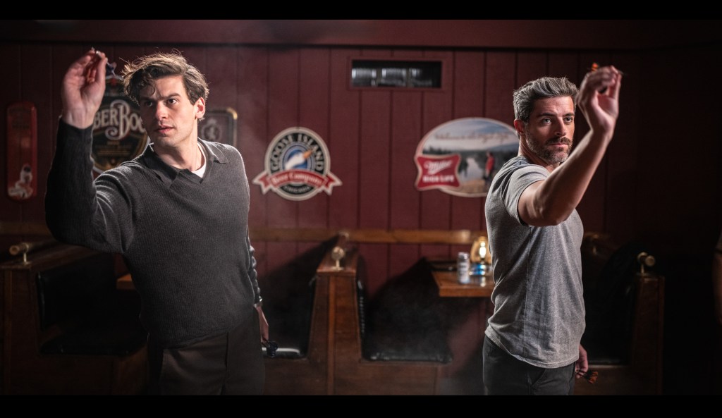 Two men shoot prepare to throw darts