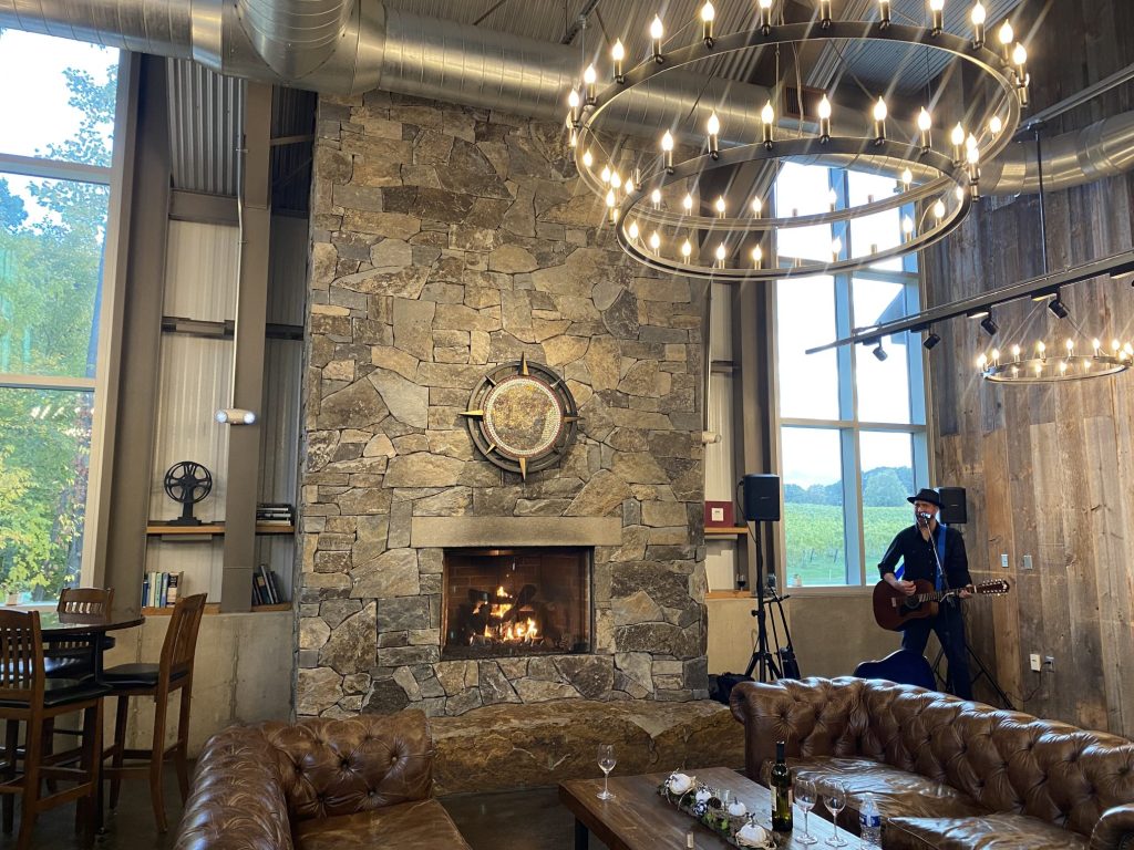 Large stone fireplace with leather couches and a guitar player.
